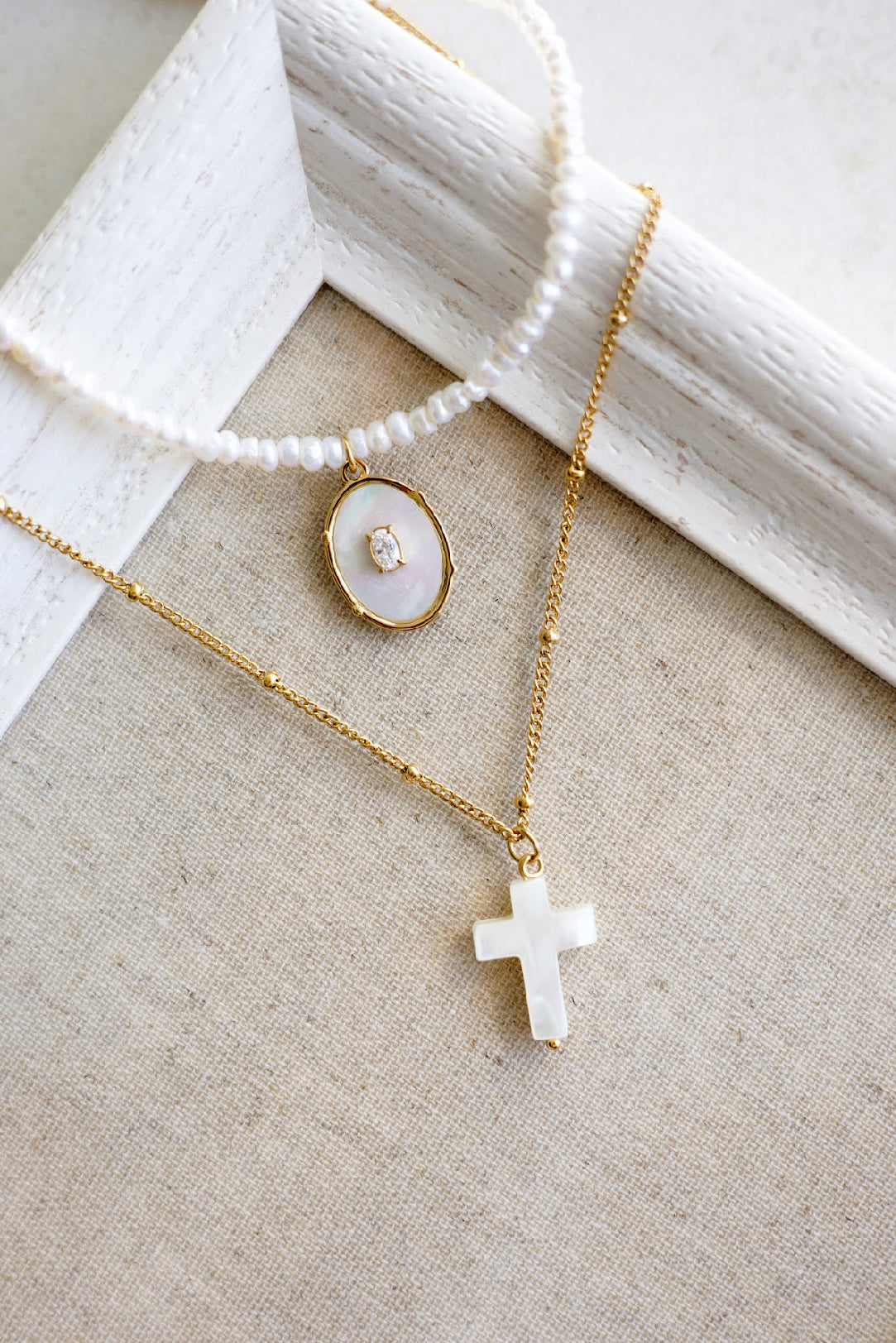 Ogrlica s križem od čelika sa pozlatom u kombinaciji rječnih bisera i sedef. 